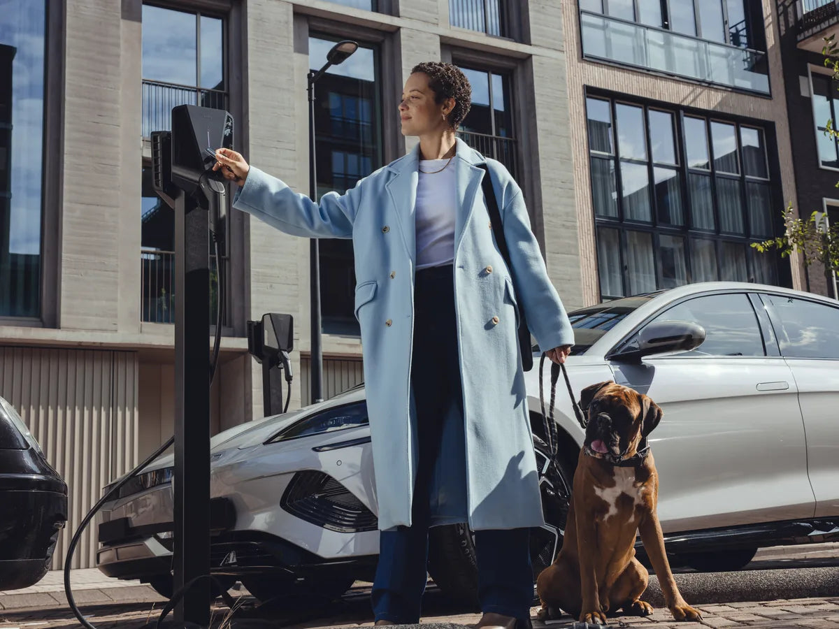 Vrouw met hond bij Easee-laadpalen op een parkeerplaats
