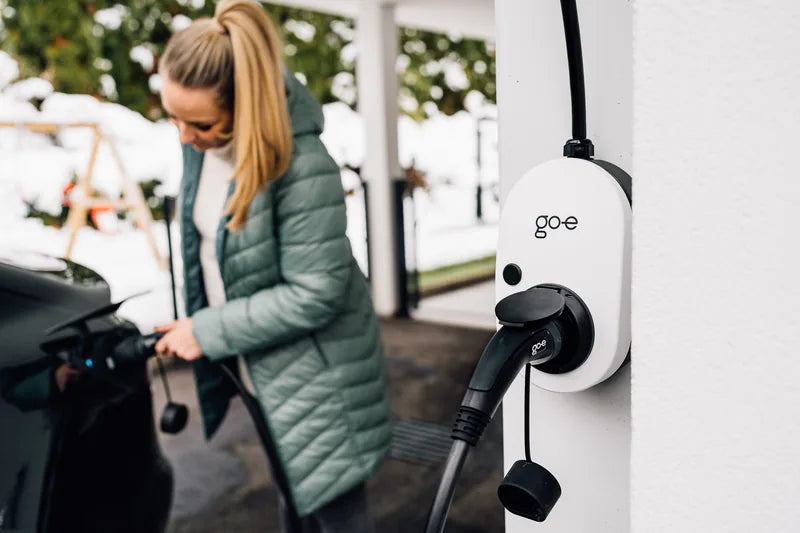 Vrouw laadt haar auto in de sneeuw aan een go-e Charger