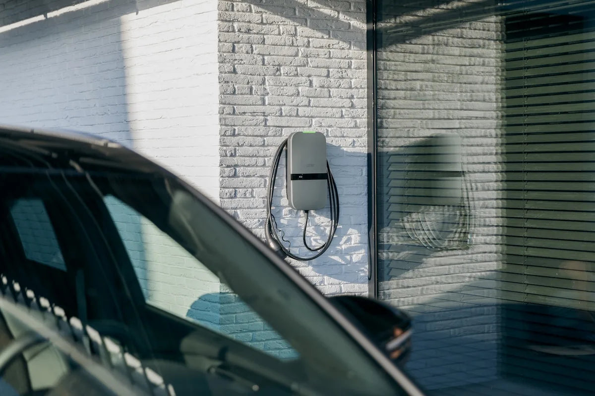 Peblar-laadpaal aan de gevel naast een geparkeerde auto